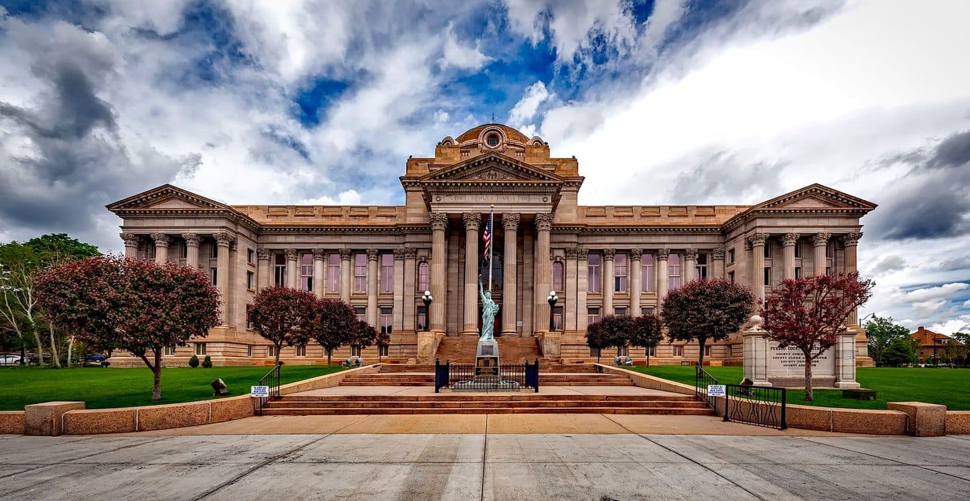 The columned front elevation of a neoclassical courthouse seen from the approach.