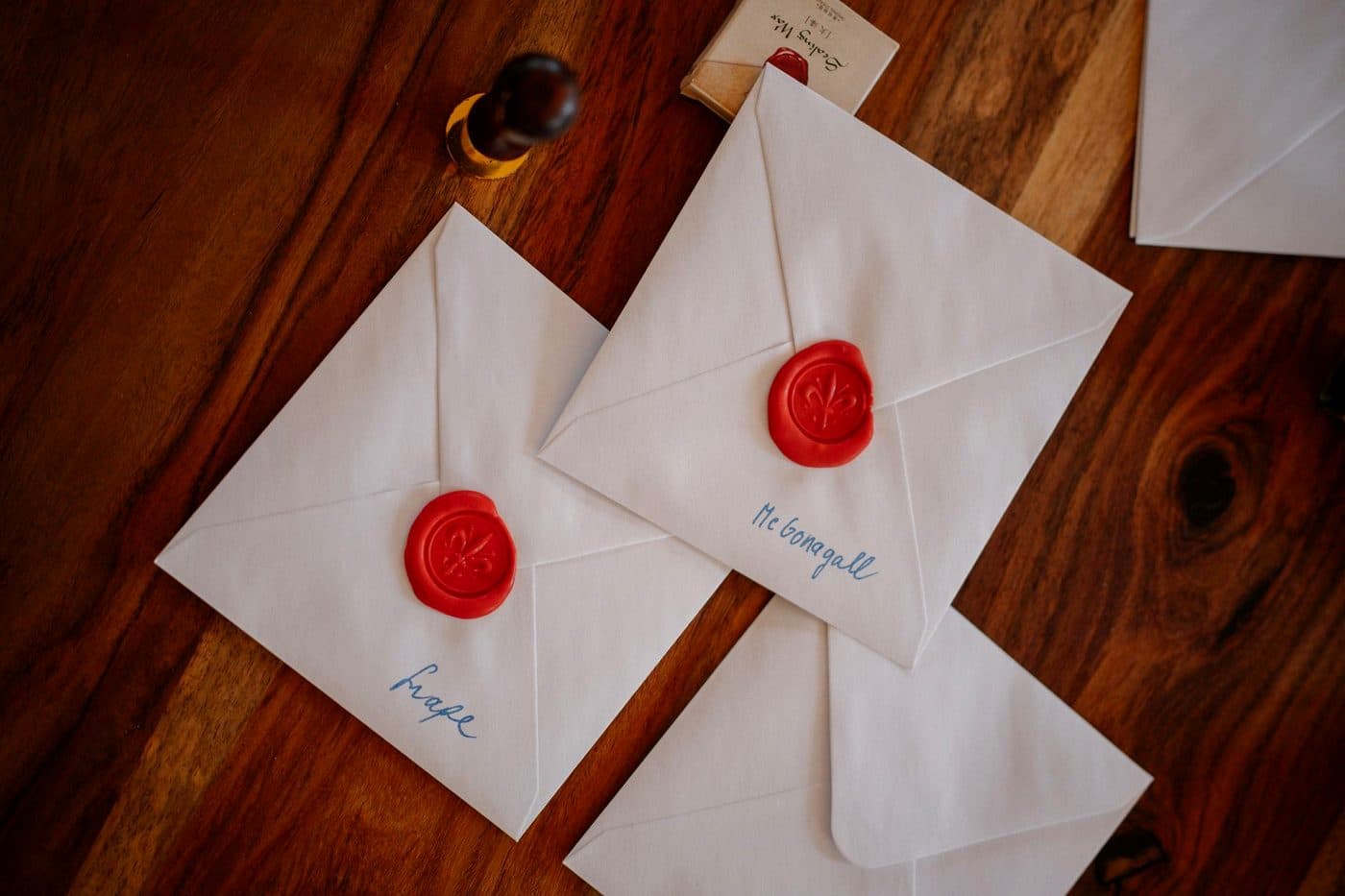 Three white envelopes closed with red wax seals, arranged on a pale surface.
