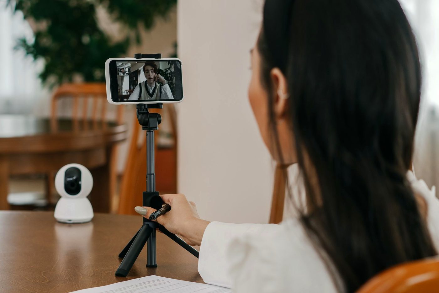 A webcam on a small tripod facing a person seated at a desk.