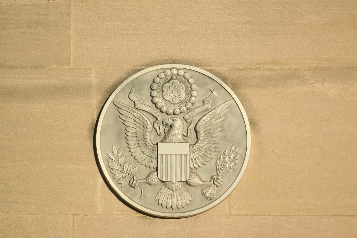 A stone carving of the Great Seal of the United States on a building facade.