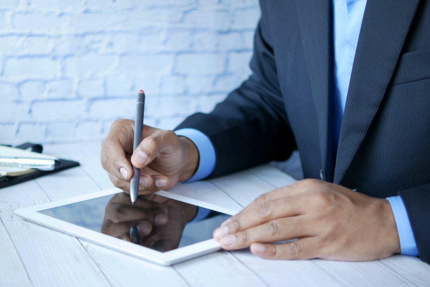 A person in a suit signing on a tablet screen with a stylus.
