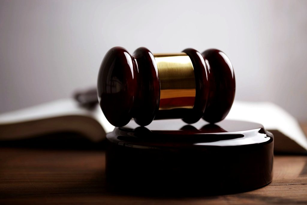 A wooden gavel resting on its sound block beside an open book.