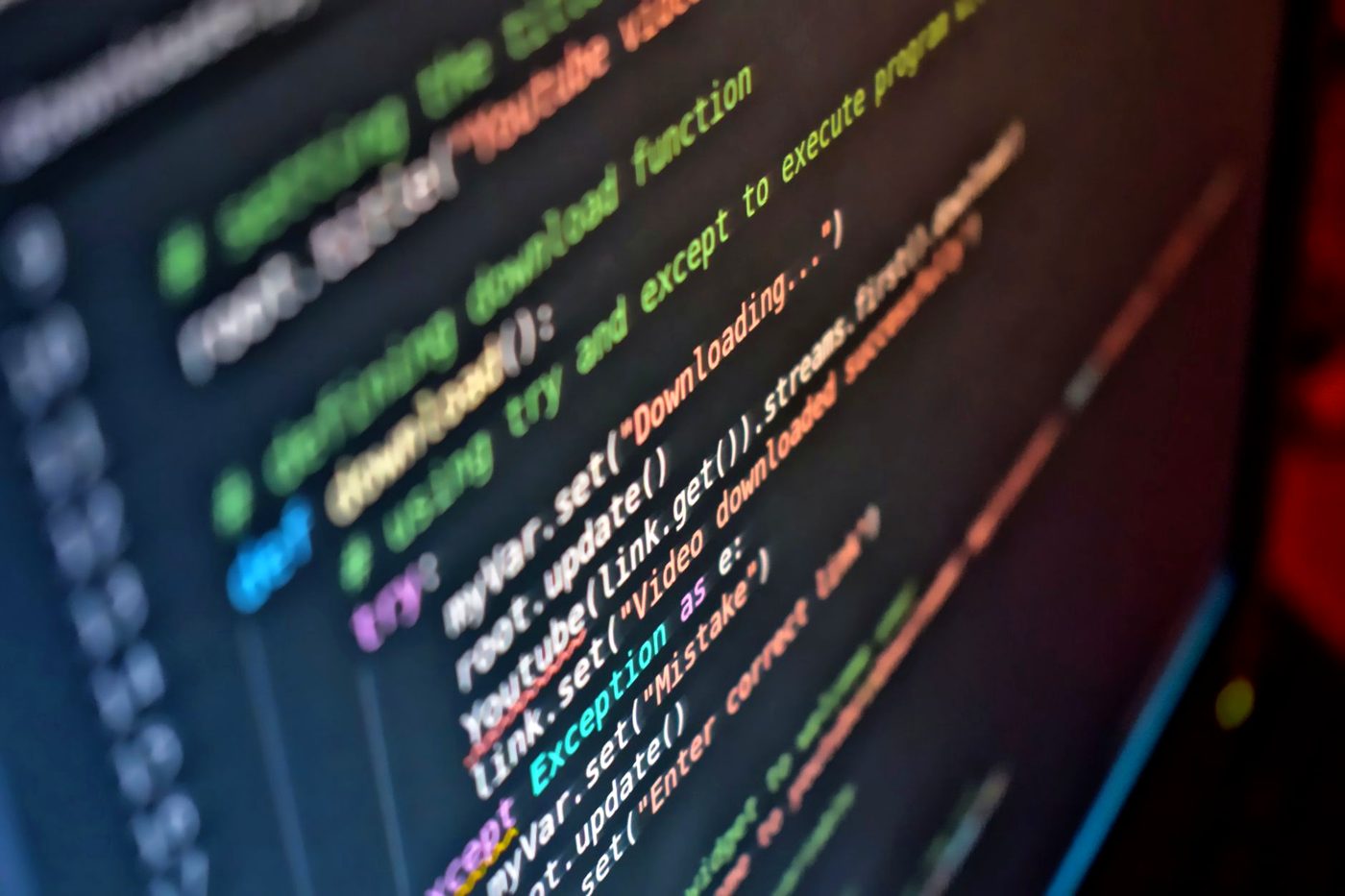 Syntax-highlighted code filling a computer screen in a darkened room.