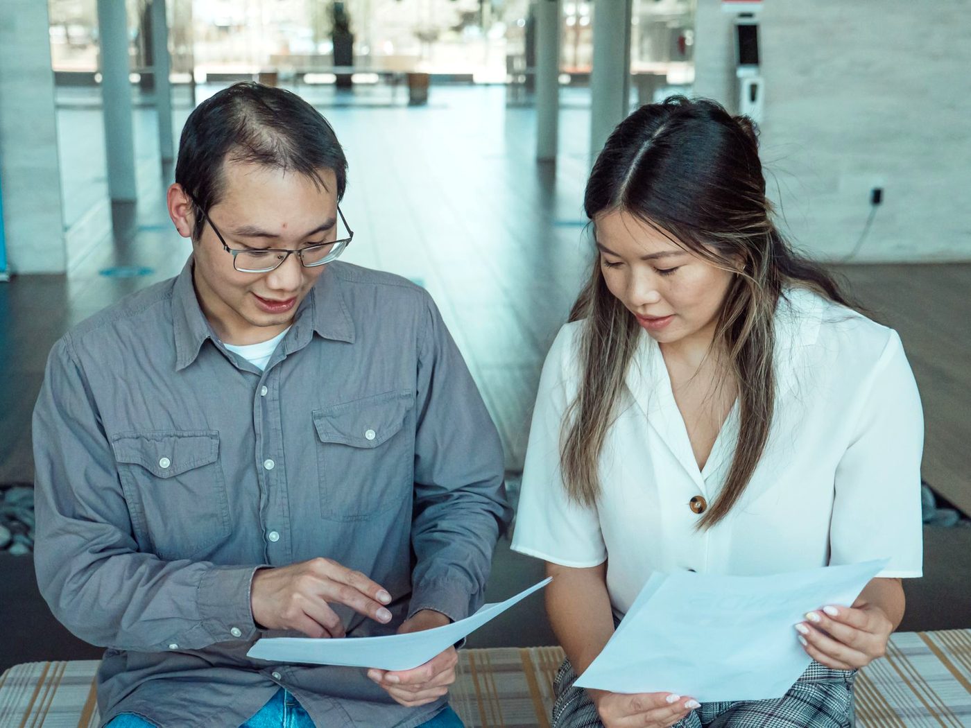 Two colleagues standing together reading through a printed document.