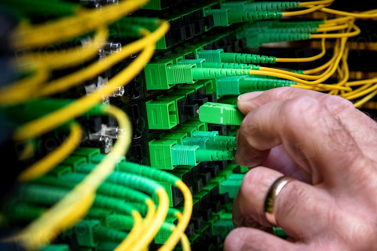 Densely bundled fiber optic cables terminating in a lit distribution panel.