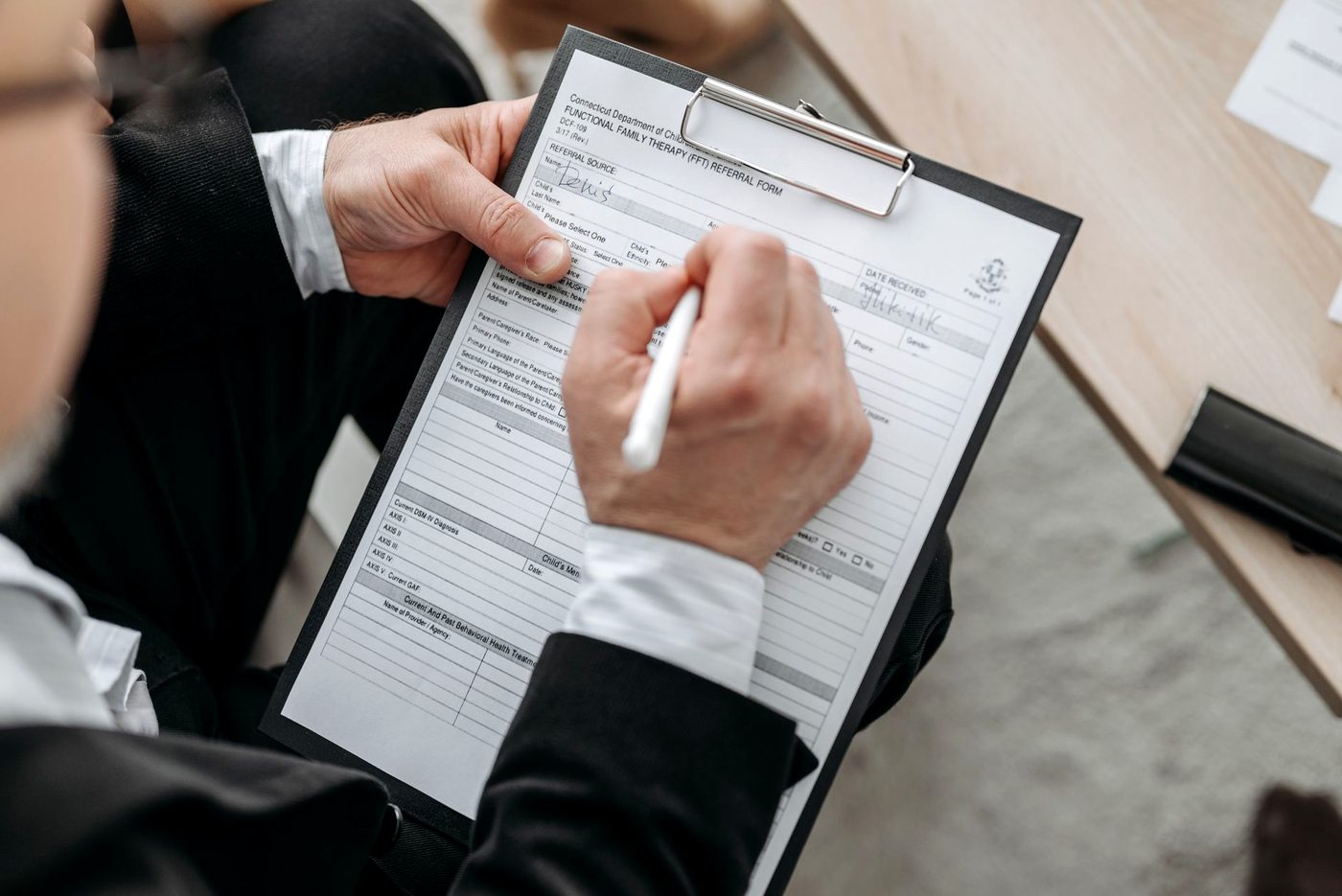 A person in a suit signing a printed form on a desk.